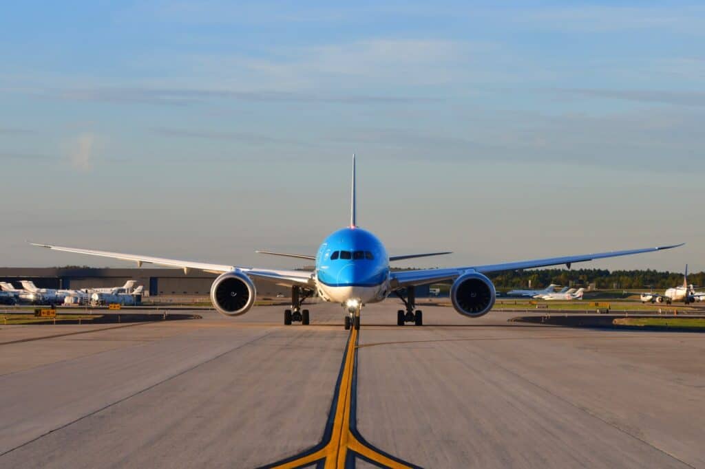A jumbo jet airplane taxing on the runway preparing to take off with the airport in the background
