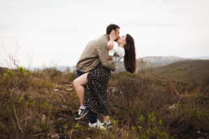 man and woman kissing in front of grassy backgroud
