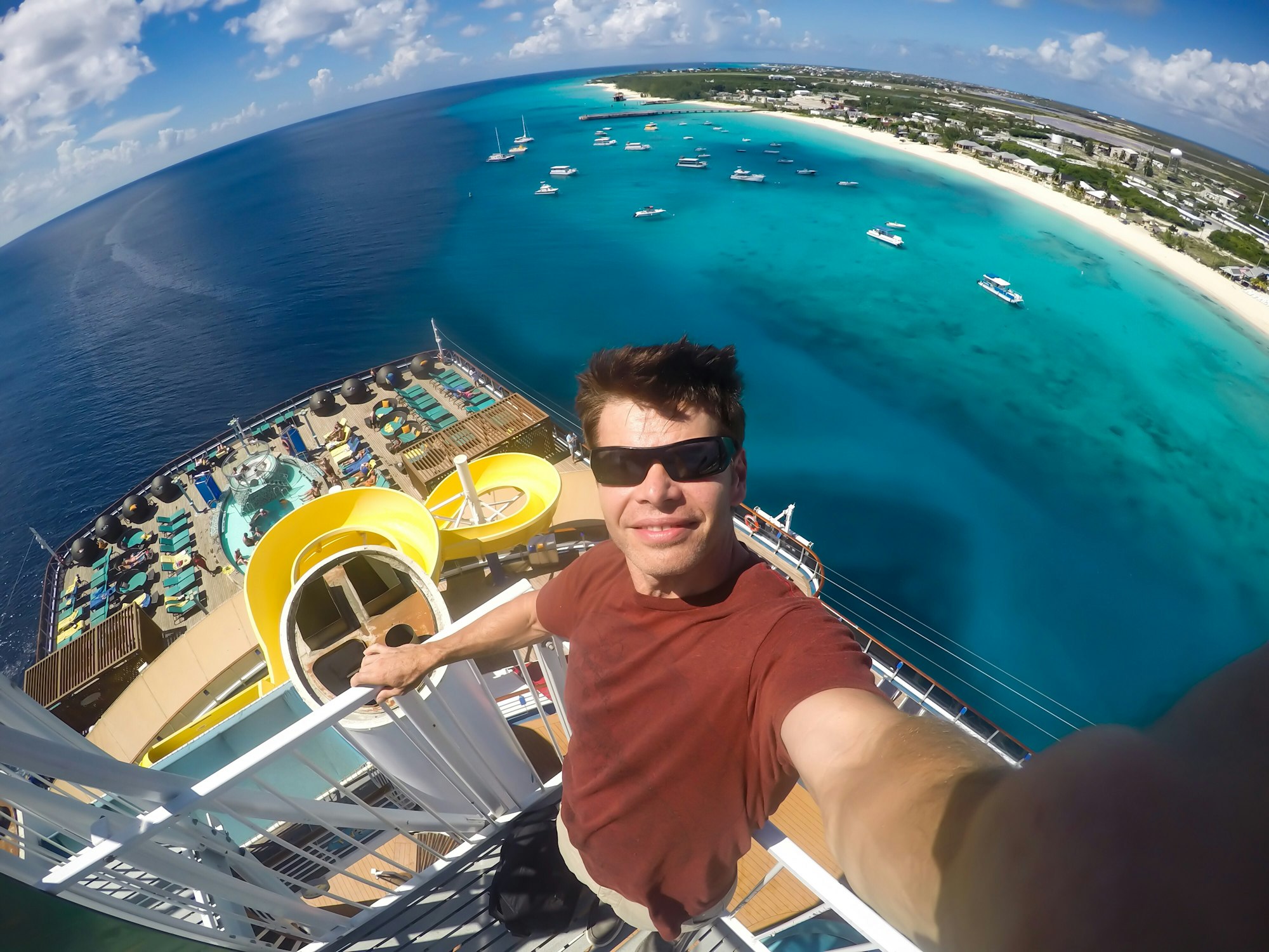 Person selfie at the top of a cruise ship with Caribbean island in the background with ocean & beach