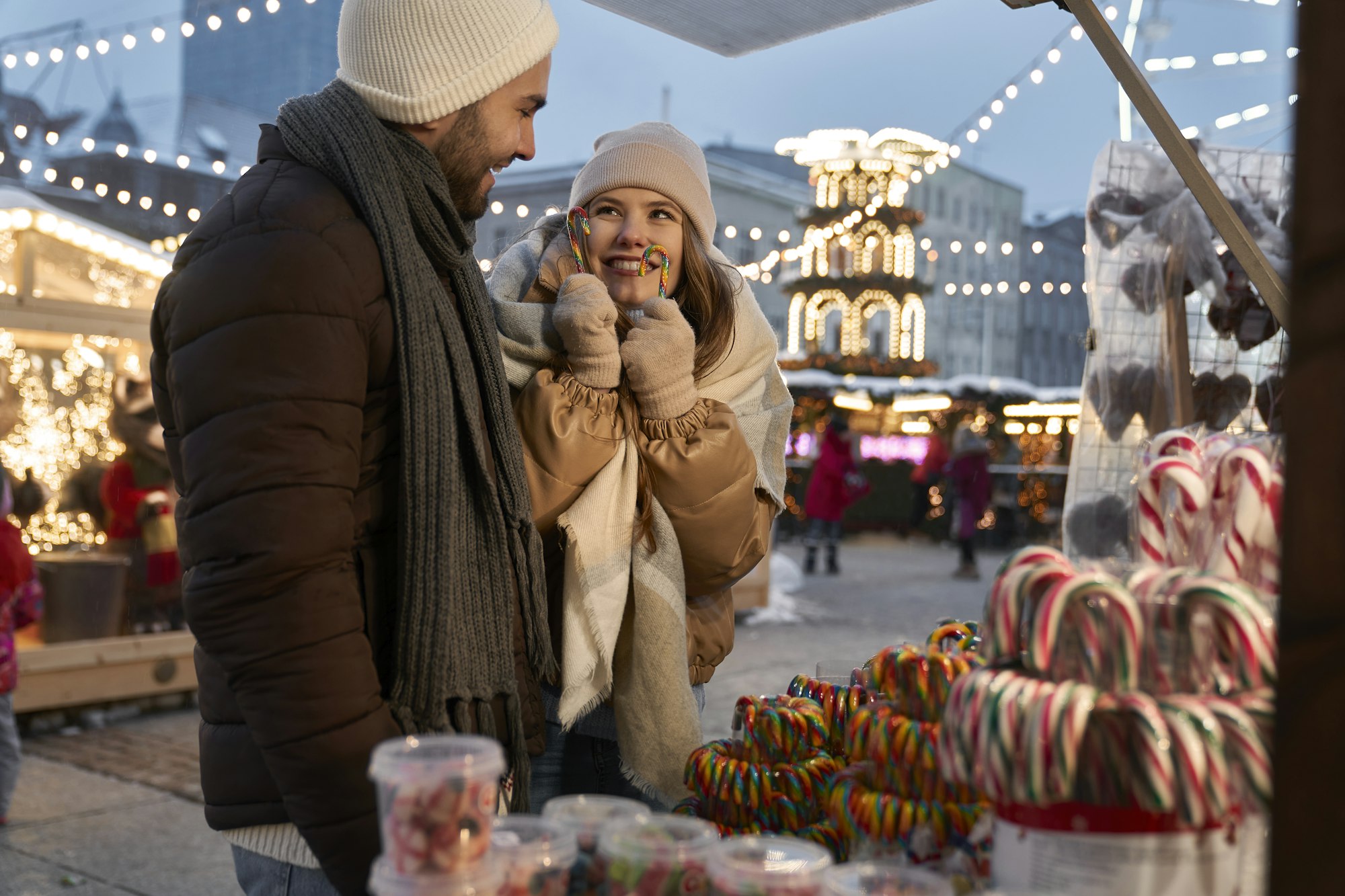 Caucasian couple buying candies on Christmas market at night