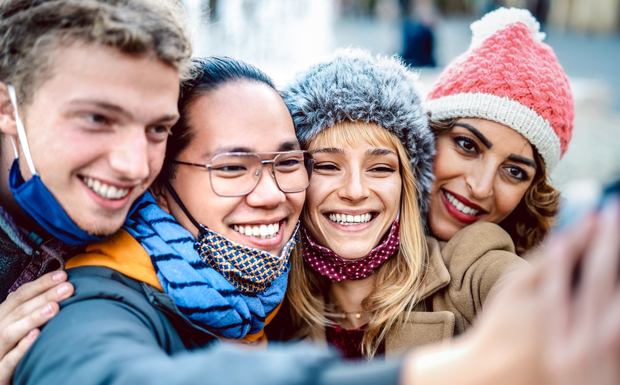 Winter travelers taking happy selfie wearing face mask and winter clothes