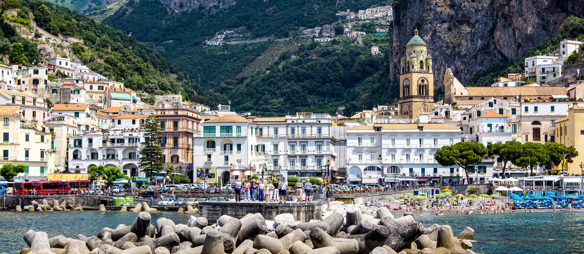 Panoramic view of small haven of Amalfi village with turquoise sea and colorful houses on slopes of
